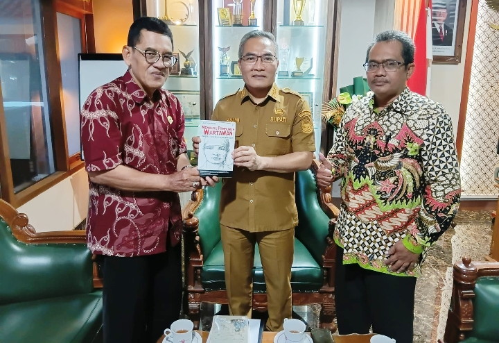 Penyerahan buku Memburu Pembunuh Wartawan Fuad Muhammad Syafruddin yang ditulis Anggota Tim Pencari Fakta PWI DIY, Asril Sutan Marajo kepada Bupati Bantul Halim Muslih. (Dok. PWI DIY)